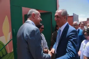 Two men shaking hands in front of a colorful outdoor mural
