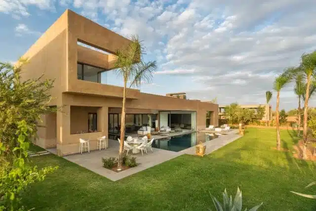 A modern eco-friendly residential complex in Marrakech showcasing sustainable architecture with solar panels and green spaces, developed through public-private partnerships.