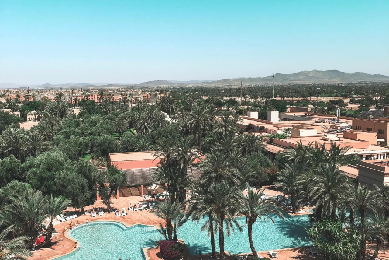 Aerial view of Marrakech with palm trees, pools, and residential areas near Morocco Mall investment zone.