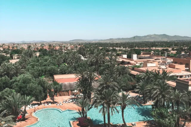 Aerial view of Marrakech with palm trees, pools, and residential areas near Morocco Mall investment zone.