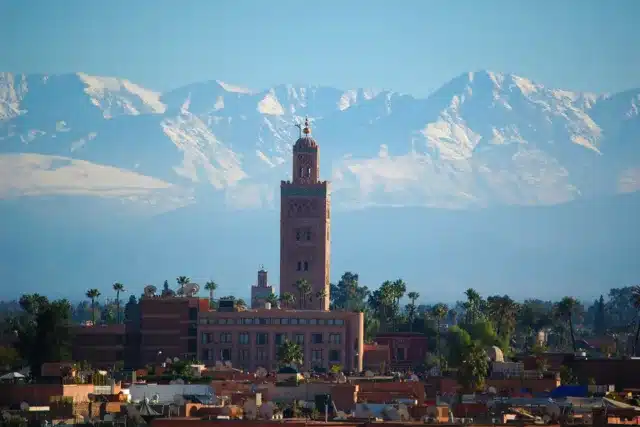 Koutoubia Mosque with Atlas Mountains, Marrakech tourism rental investment.