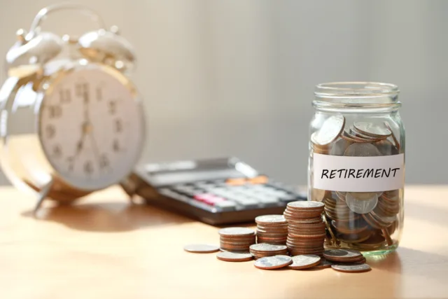 Coins in jar labelled 'retirement' with clock and calculator for retirement planning to buy retirement properties in Marrakech.
