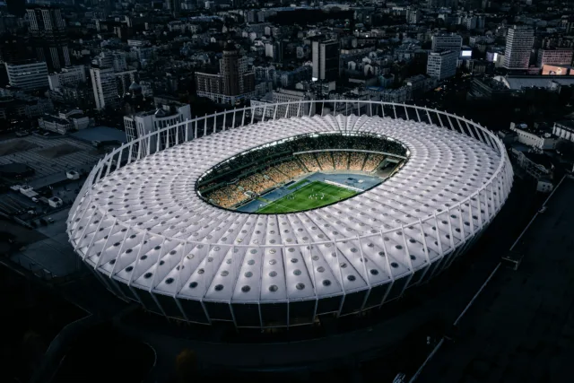 Aerial view of a modern football stadium full of fans, symbolizing economic growth and real estate market after World Cup events.